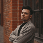 man with crossed arms leaning back against the wall